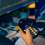 Trader analyzing stock market charts on computer screens with calculator.
