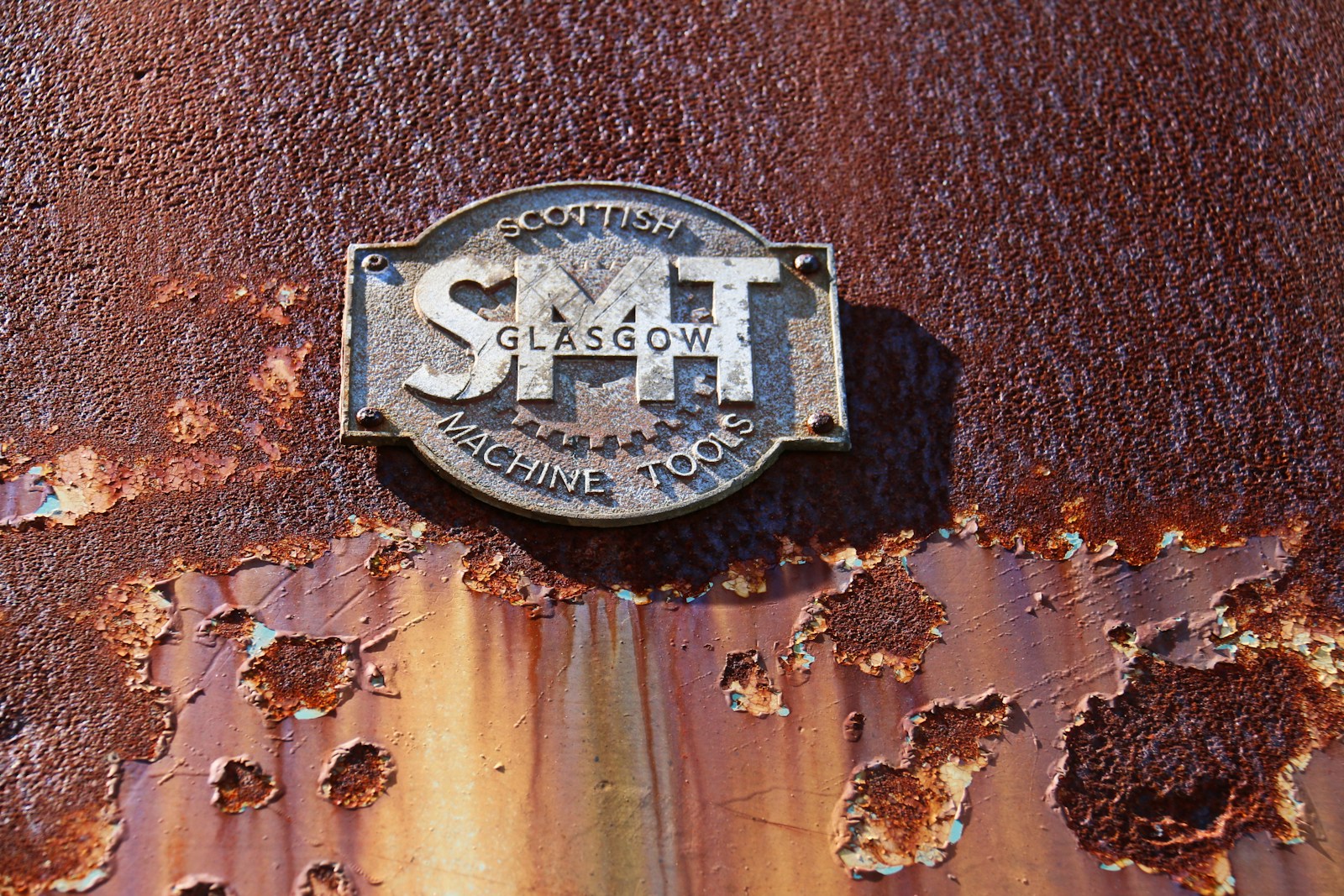 Close-up of a rusty metal plaque with smt glasgow inscription.