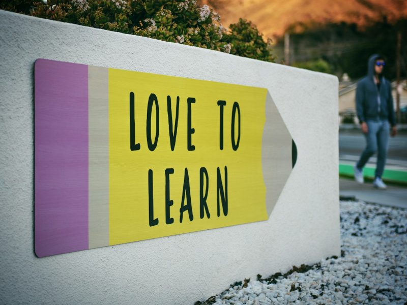 love to learn pencil signage on wall near walking man